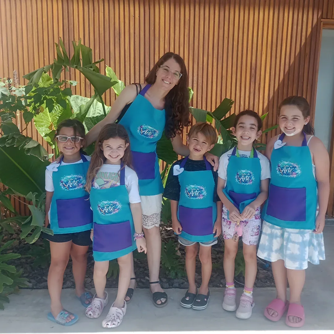 Carmen junto a un grupo de chicos y chicas de 5 a 8 años con sus delantales de arte