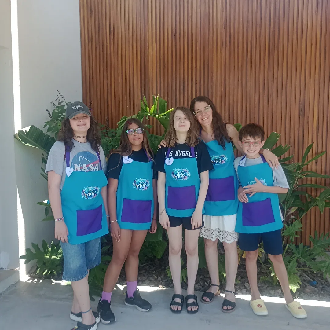 Carmen junto a un grupo de chicos y chicas de 9 a 12 años con sus delantales de arte